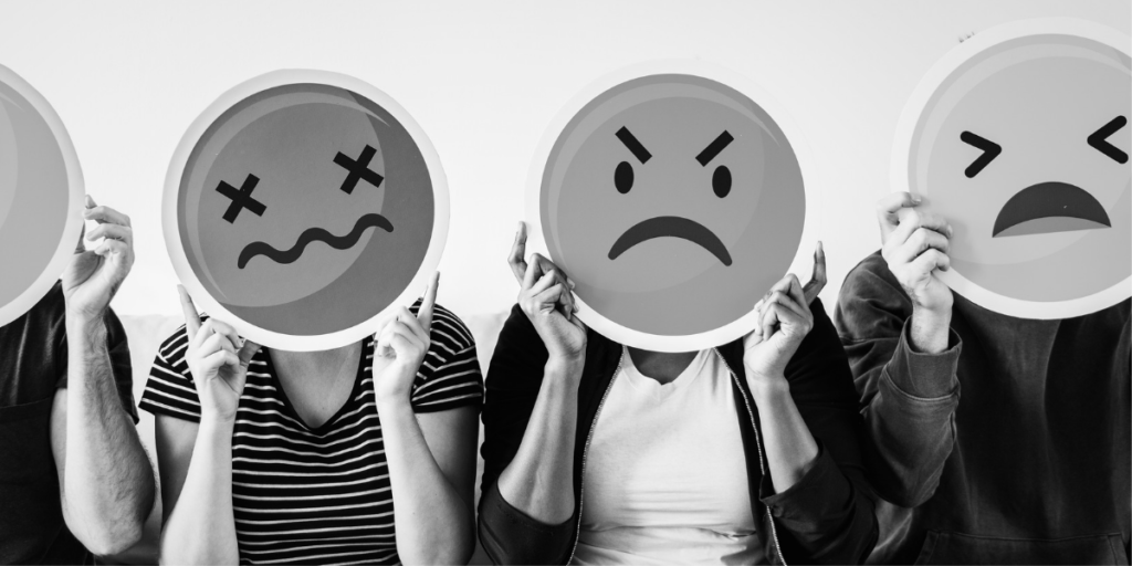 Imagem de pessoas segurando placas de emojis insatisfeitos, bravos e tristes.